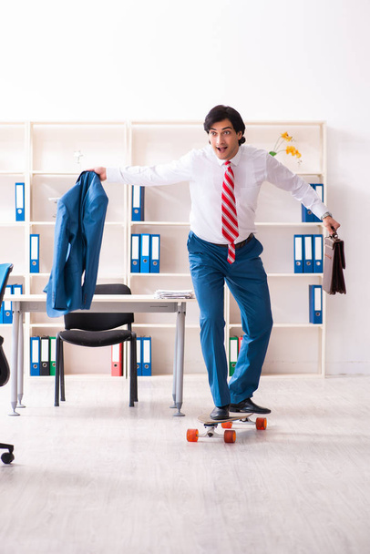 Young handsome businessman with longboard in the office  - Photo, Image