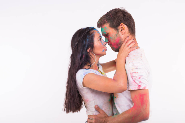 Holiday, holi and people concept - Happy couple having fun covered in paint on white background - Foto, Bild