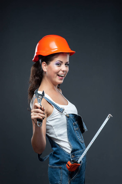 Woman builder worker with wrench standing against grey backgroun - Photo, Image