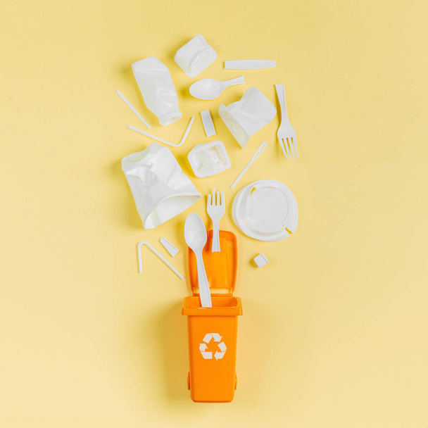 Λευκό ενιαία χρήση πλαστικού σε κάδο απορριμμάτων σε κίτρινο φόντο - Φωτογραφία, εικόνα