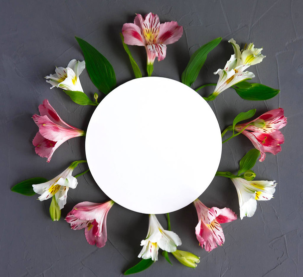 Mock up blank paper and envelope on dark wooden background with natural flowers of white color. Blank, frame for text. Greeting card design with flowers. Aalstroemeria on wooden background. View from  - 写真・画像