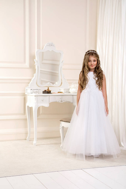 Muotokuva söpö pieni tyttö valkoinen mekko ja seppele ensimmäinen pyhä ehtoollinen tausta kirkon portti - Kuva. Nuori mallivalkoinen ehtoollinen mekko seisoo tyylikäs palatsi
 - Valokuva, kuva