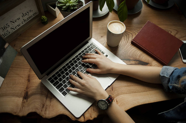 Una ragazza in un caffè con un computer portatile funziona in un posto accogliente con una tazza di caffè, ottiene piacere. Il concetto di freelance
 - Foto, immagini