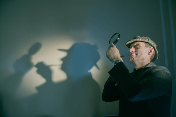 detective at work with magnifying glass and pipe investigating crimes - Foto, afbeelding