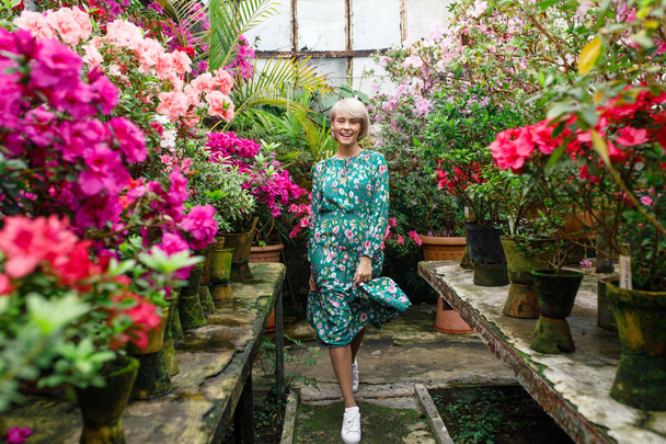 portrét mladé krásné blond ženy v zelených šatech v krásná botanická zahrada s květinami - Fotografie, Obrázek