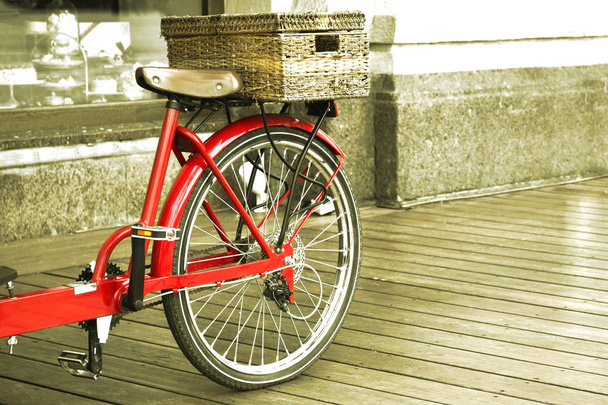 Blick von der Rückseite eines roten Fahrrads auf ein graues Gebäude. - Foto, Bild