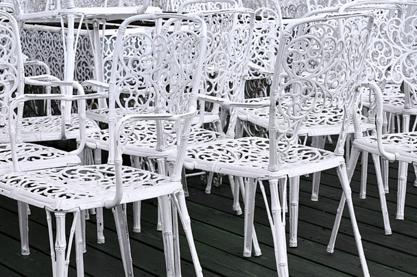 Вид белых металлических стульев, стоящих на зеленом полу
. - Фото, изображение