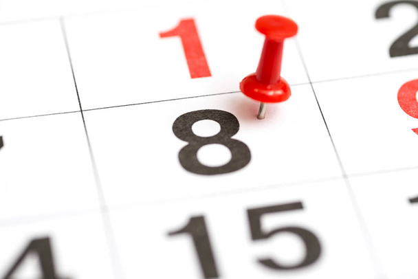 Pin auf der Datumsnummer 8. achter Tag des Monats ist mit einem roten Daumenknauf markiert. Anstecknadel im Kalender - Foto, Bild