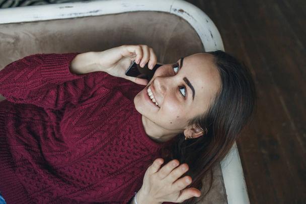 Portrait of young smiling woman talking on mobile phone on sofa at home - Φωτογραφία, εικόνα