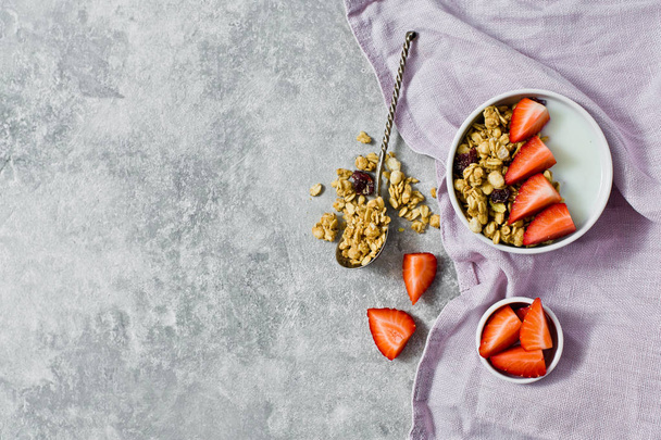 Muesli bowl with granola, strawberries and yogurt. Gray background, top view, space for text - Foto, afbeelding