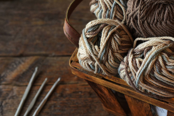 A close up image of crochet yarn and crochet hooks on a vintage wooden table.  - Photo, image
