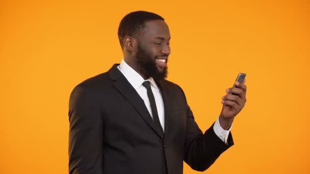 Successful afro-american businessman reading news on phone, making yes gesture - Filmmaterial, Video