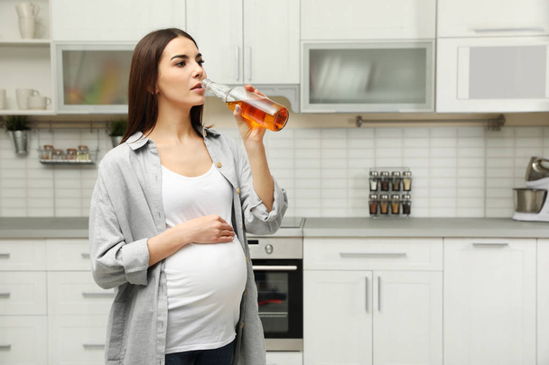 Future mother drinking alcohol in kitchen. Bad habits during pregnancy - Foto, Bild