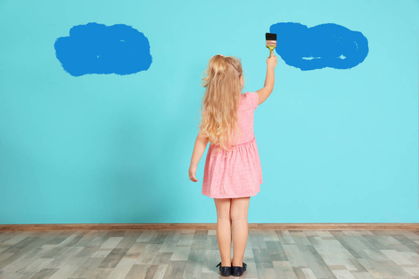 Little child painting with brush on color wall - Φωτογραφία, εικόνα