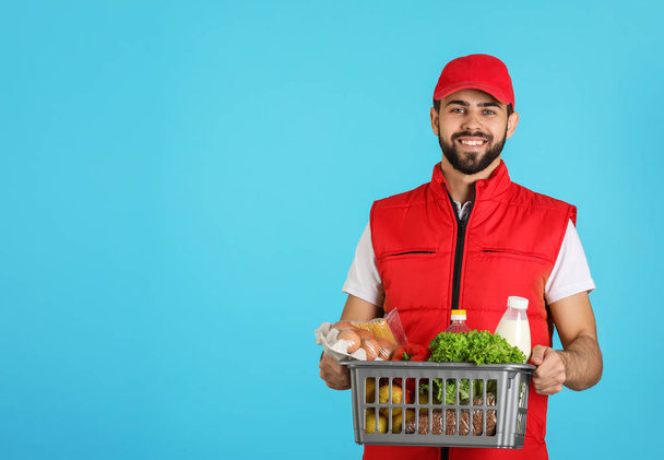 Man holding basket with fresh products on color background, space for text. Food delivery service - Foto, afbeelding