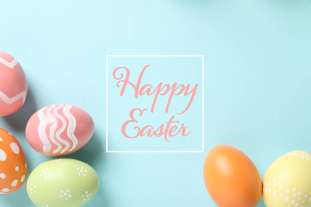 Flat lay composition of colorful painted eggs and text Happy Easter on color background - Фото, зображення