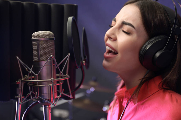 Young singer with microphone recording song in studio - Foto, immagini