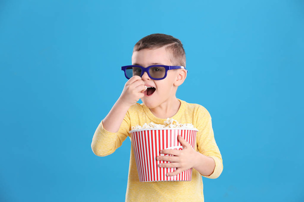 Cute little boy with popcorn and glasses on color background - Foto, immagini