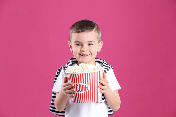 Cute little boy with popcorn on color background - Foto, Imagen