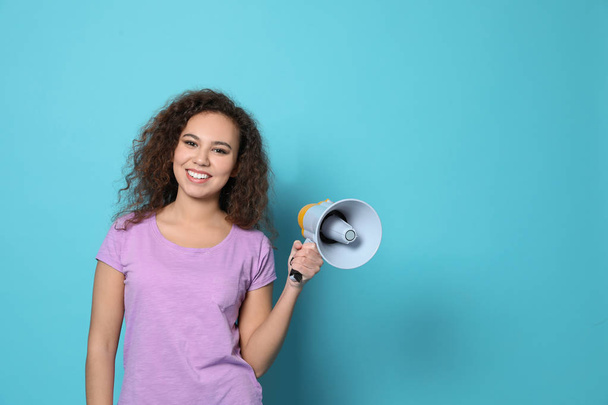 Young African-American woman with megaphone on color background. Space for text - Photo, image