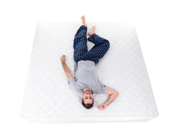 Young man sleeping on mattress against white background, above view - Фото, зображення