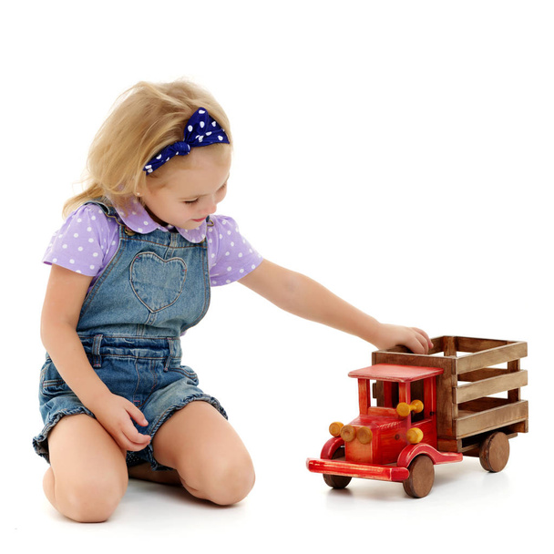 Little girl is playing with a wooden car. - Foto, Imagem