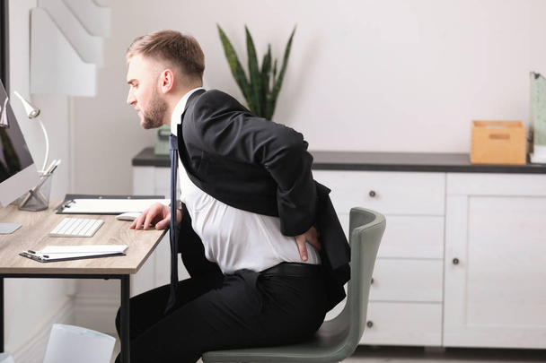 Businessman suffering from back pain at workplace - Fotoğraf, Görsel