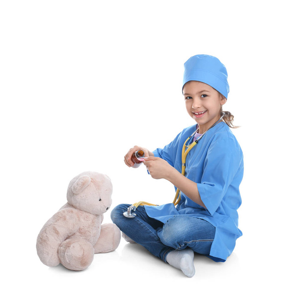 Cute child playing doctor with stuffed toy on white background - Photo, Image