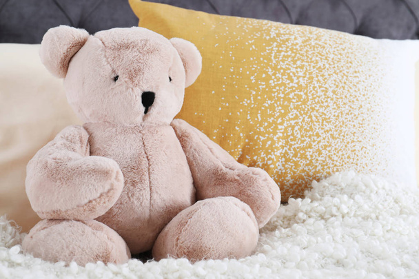 Cute teddy bear sitting on bed indoors. Space for text - Foto, Bild