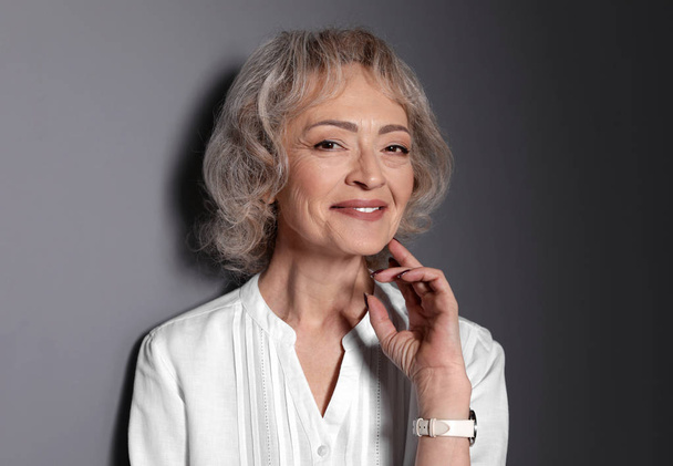 Portrait of mature woman on grey background - Foto, Imagem