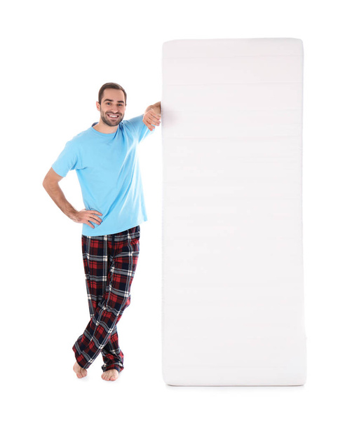 Young man with comfortable mattress isolated on white - Foto, Imagem