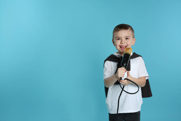Cute funny boy with microphone on color background. Space for text - Zdjęcie, obraz