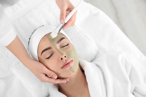 Cosmetologist applying mask on client's face in spa salon, above view - Foto, imagen