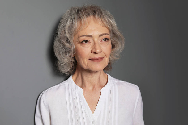 Portrait of mature woman on grey background - Valokuva, kuva