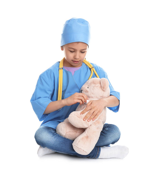 Cute child playing doctor with stuffed toy on white background - Fotografie, Obrázek
