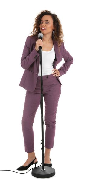Curly African-American woman in suit posing with microphone on white background - 写真・画像