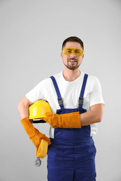 Male industrial worker in uniform on light background. Safety equipment - Foto, Bild