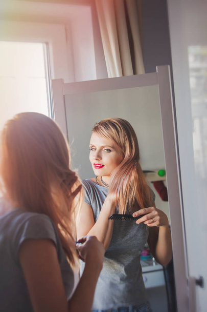 rubia mujer aplicando cosméticos cerca del espejo
  - Foto, imagen