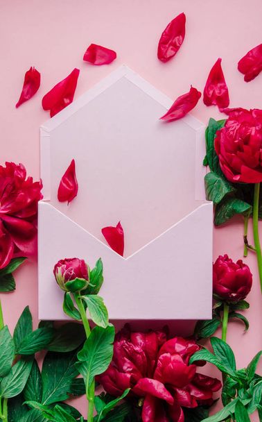 Piros friss pünkösdi rózsa és boríték  - Fotó, kép