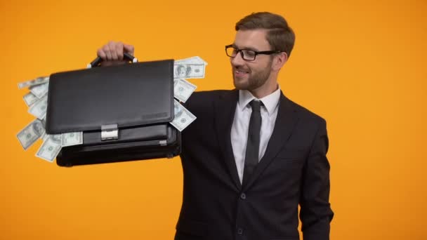 Man showing case packed with money, winking and doing thumbs-up, loan, credit - Filmati, video