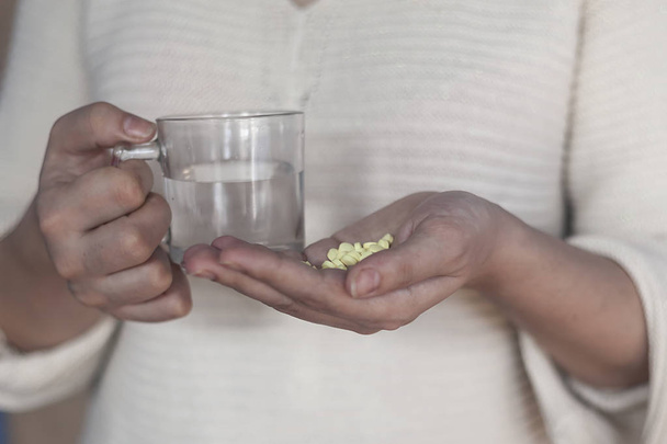 Pile of pills and glass of water in female hands - Photo, Image