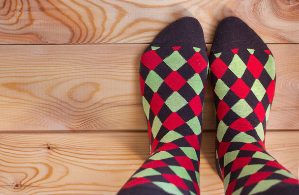 zwei Beine in bunten Socken auf einem Holzboden.  - Foto, Bild