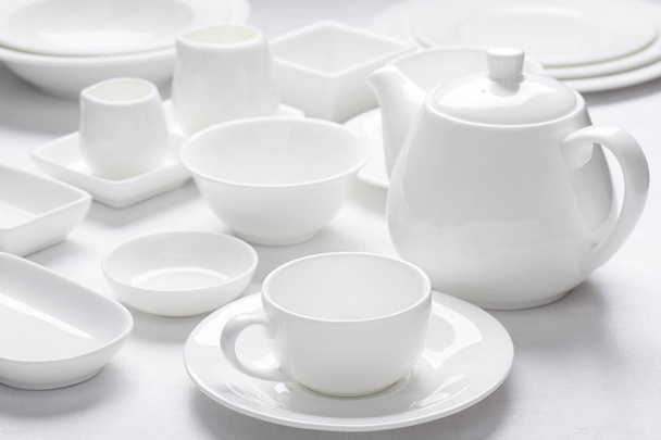 Set white dishes on white wooden surface - 写真・画像