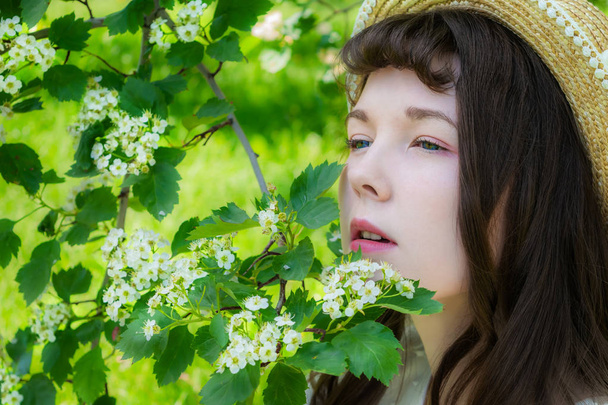 Girl in a garden in hawthorn flowers  - Foto, afbeelding
