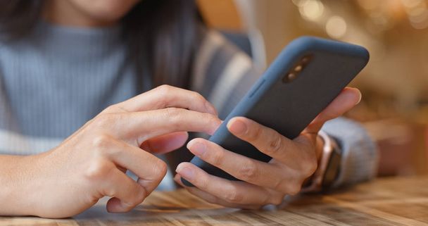 Жінка використовує мобільний телефон в ресторані
 - Фото, зображення