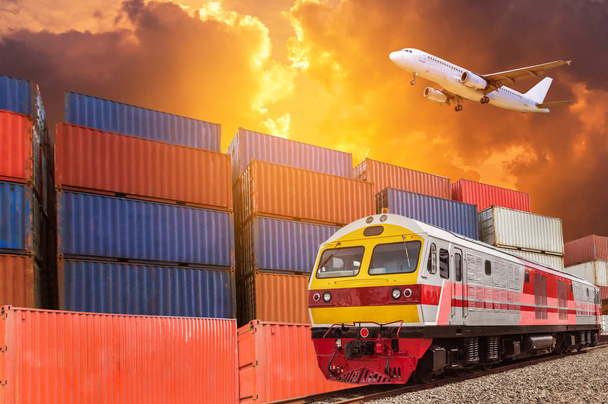 Global business with commercial cargo freight train and container cargo stack and trailer at the dock during cargo plane flying above on sunset time. logistics transportation delivery import export concept. - Photo, Image