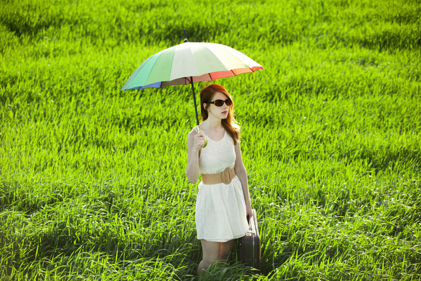 Redhead enchantress with umbrella and suitcase at spring country - Fotografie, Obrázek
