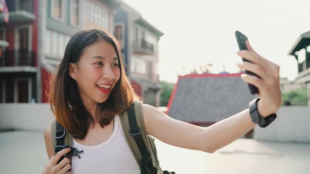 Vrolijke mooie jonge Aziatische backpacker blogger vrouw met behulp van smartphone selfie te nemen terwijl het reizen in Chinatown in Peking, China. Levensstijl rugzak concept van toeristische reizen vakantie. - Foto, afbeelding