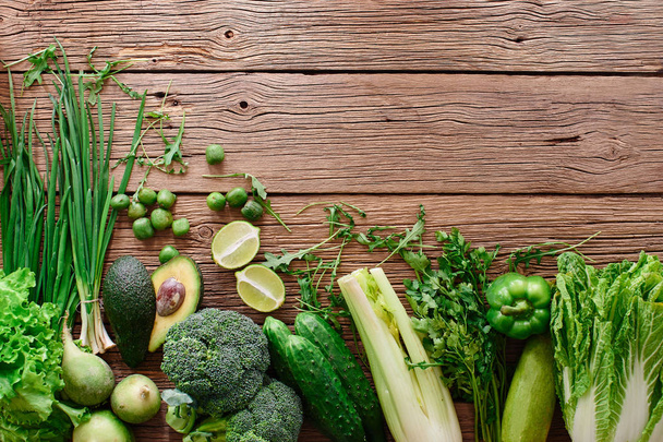 Verduras verdes frescas y frutas y verduras sobre un fondo de madera con espacio para copiar. Concepto de alimentación saludable
 - Foto, imagen