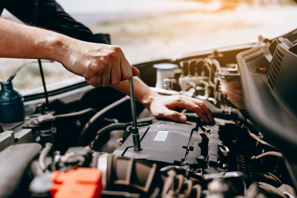 Araba tamircisi otomobilin motoru kutusunu açmak için bir anahtar kullanır. - Fotoğraf, Görsel